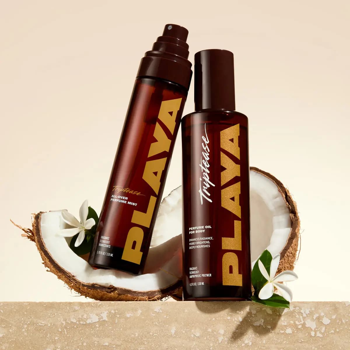 Triptease mist and Perfume Oil for Body bottles leaning together in front of a split coconut on a stone ledge