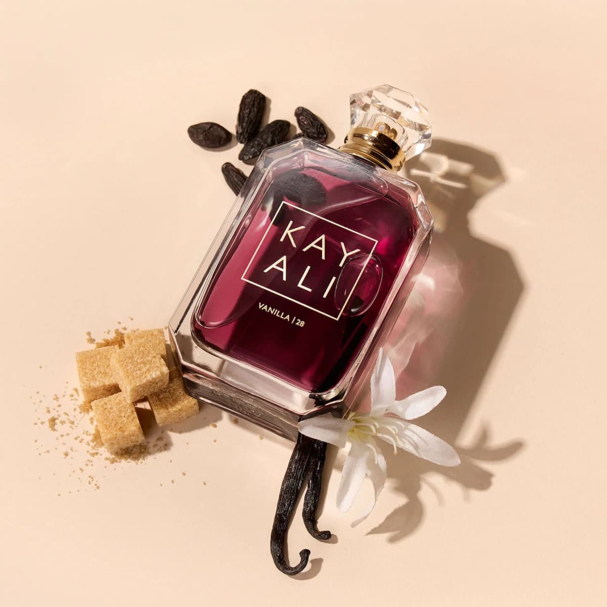 Vanilla | 28 bottle lying among tonka beans, vanilla pods, brown sugar cubes and a white orchid flower