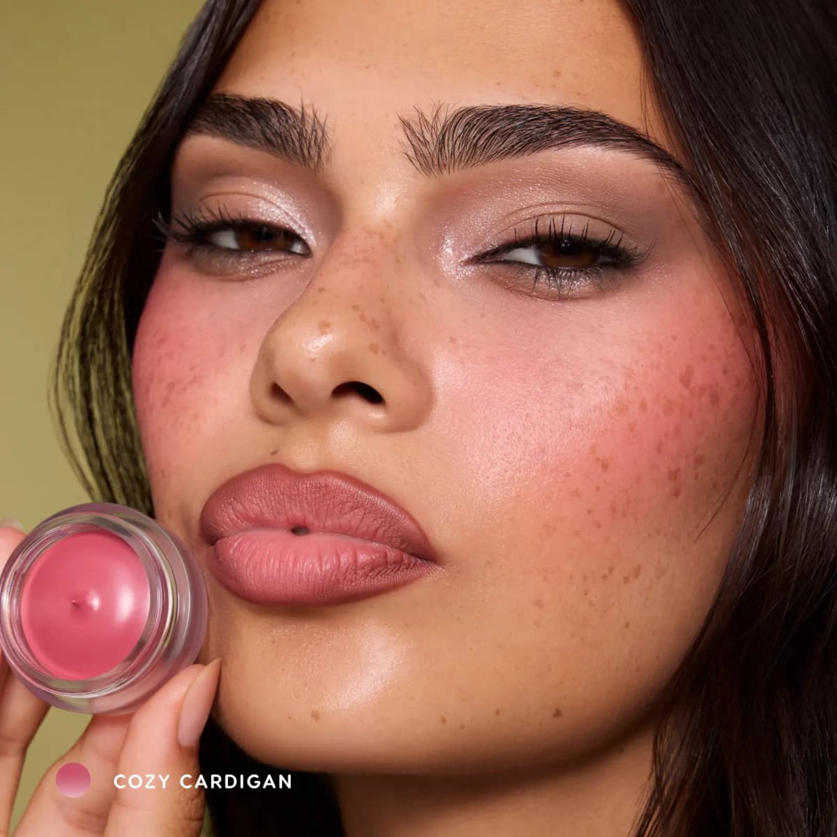 Freckled model holding a Cozy Cardigan pot to her cheek, wearing pink blush and matte mauve lips