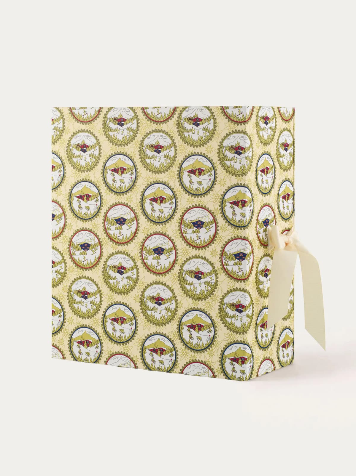 Closed advent calendar box with alpine cameo pattern and cream ribbon bow on the side against a plain background