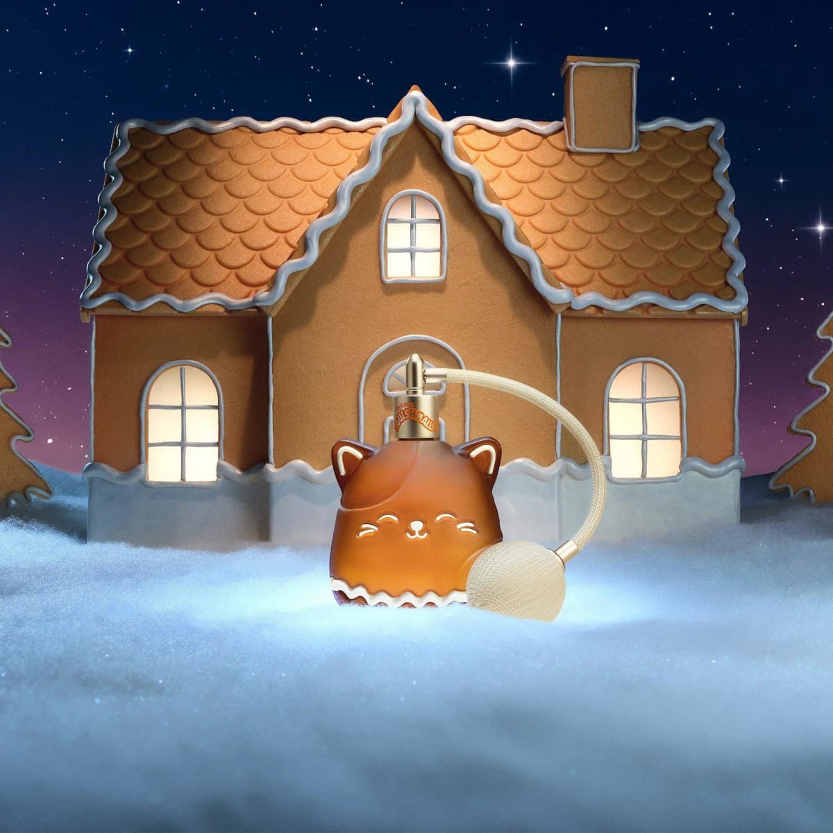 Cam the Cat perfume bottle on snow before a lit gingerbread house with icing trim under a starry night sky