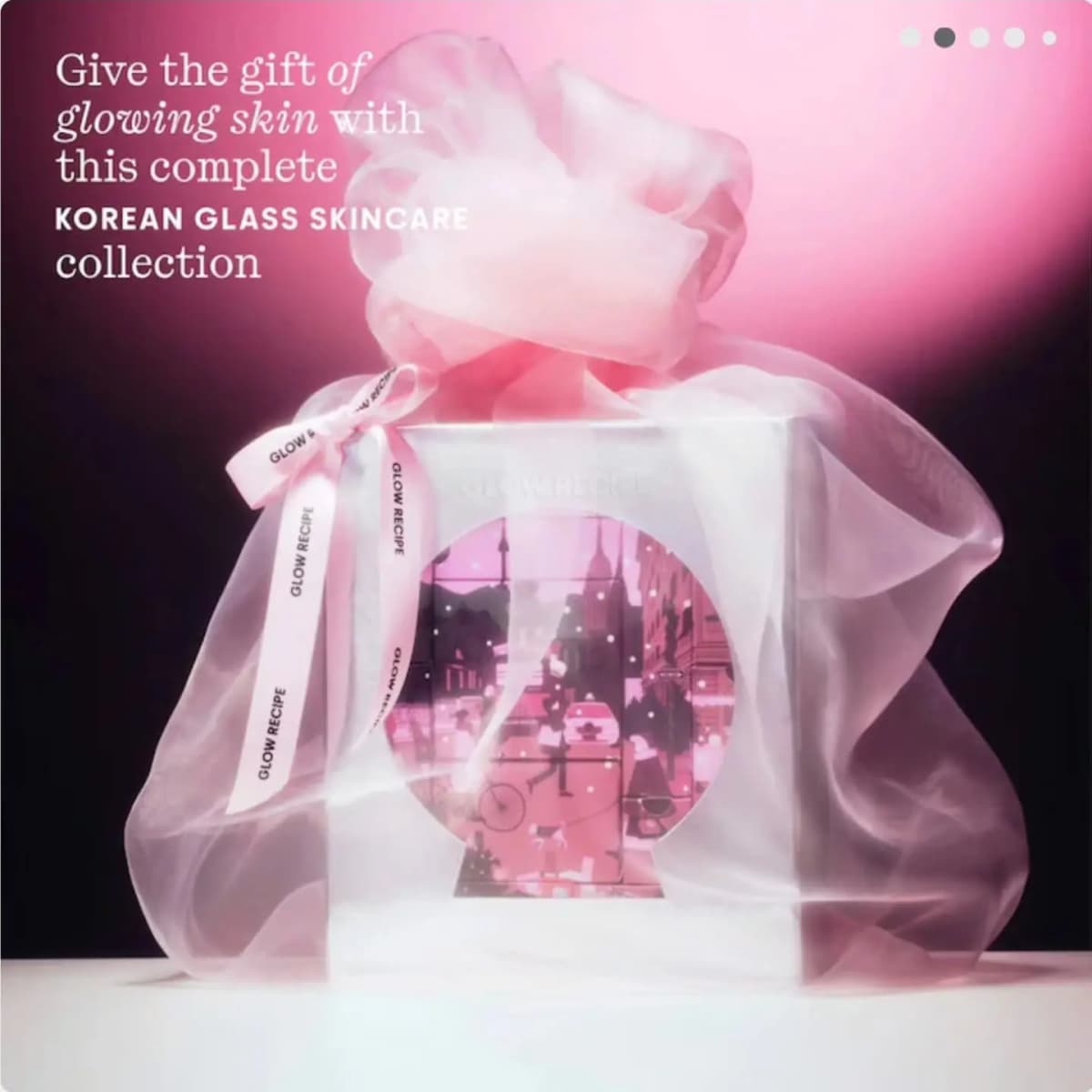 Glow Recipe advent calendar wrapped in sheer pink organza with a branded ribbon bow against a pink-to-black backdrop