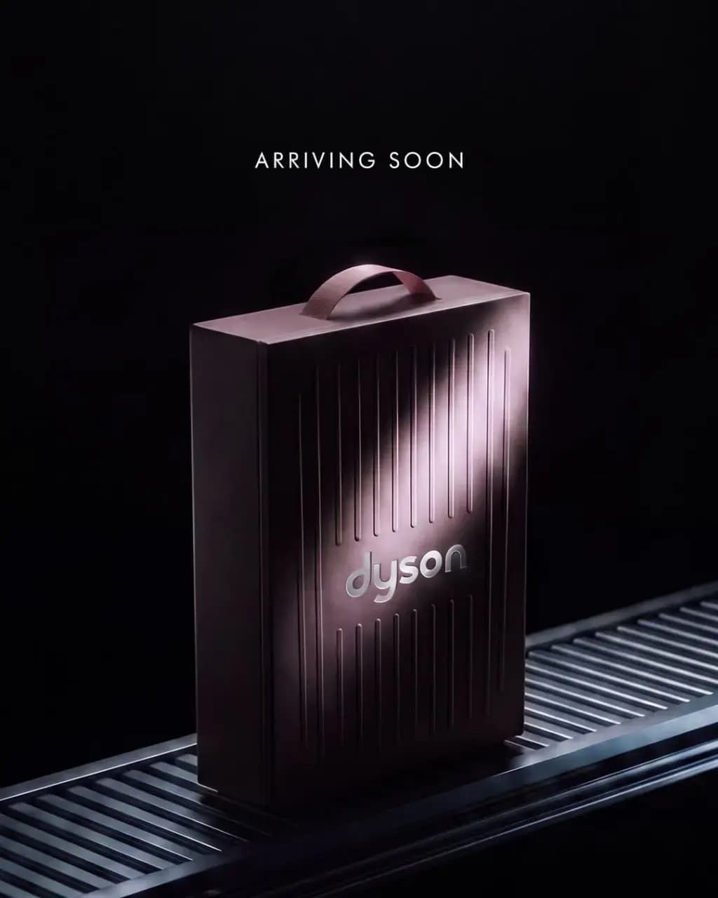 The ribbed Dyson box on a ridged surface in dark light, captioned "ARRIVING SOON"