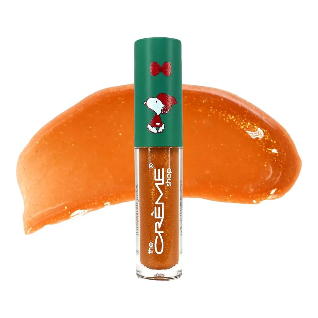 Shimmering Lights lip oil with green Snoopy cap in front of a shimmery caramel-amber swatch.