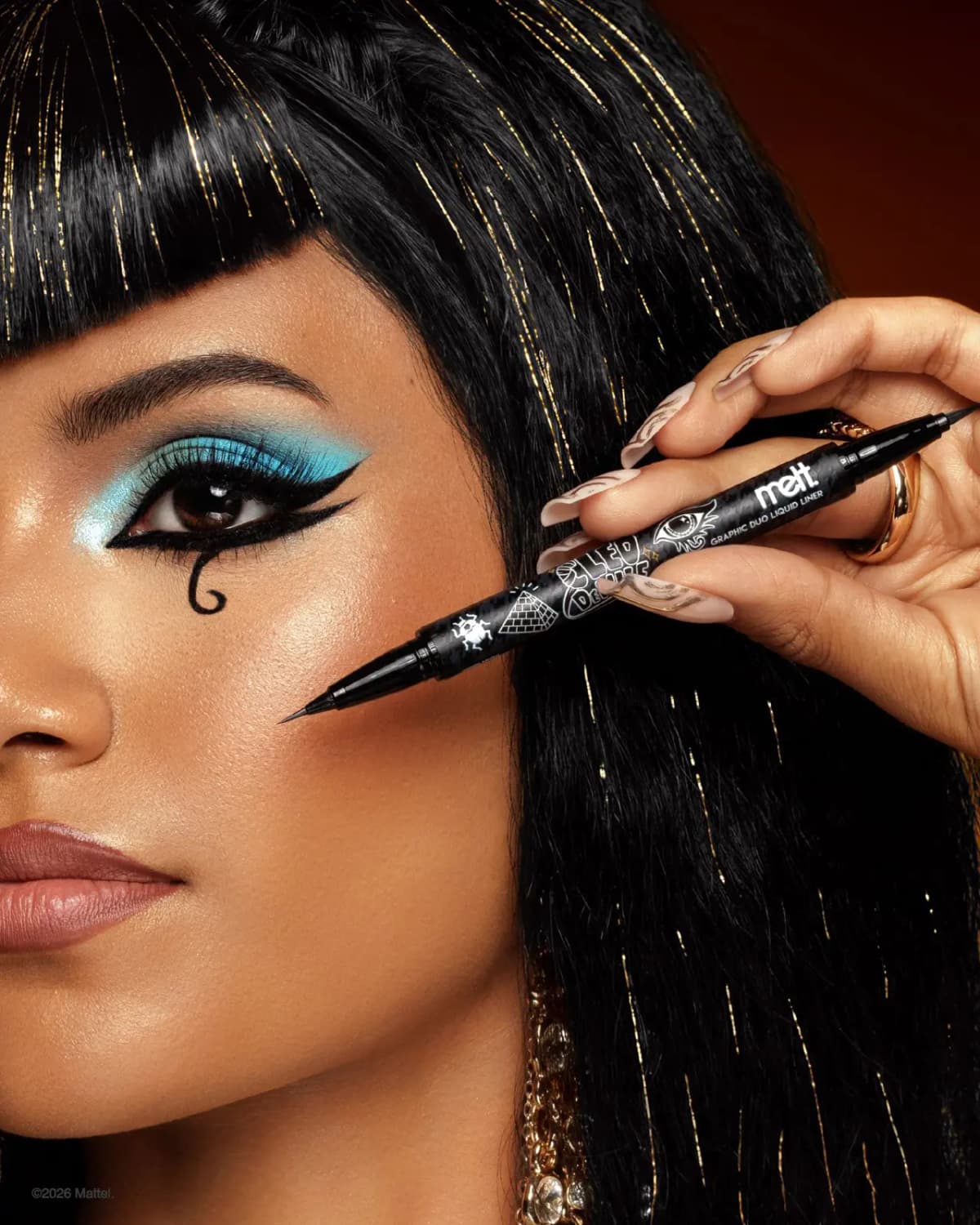 Model with Cleo-style black bangs, turquoise shadow and graphic winged liner holds the black Cleo De Nile dual-tip liner