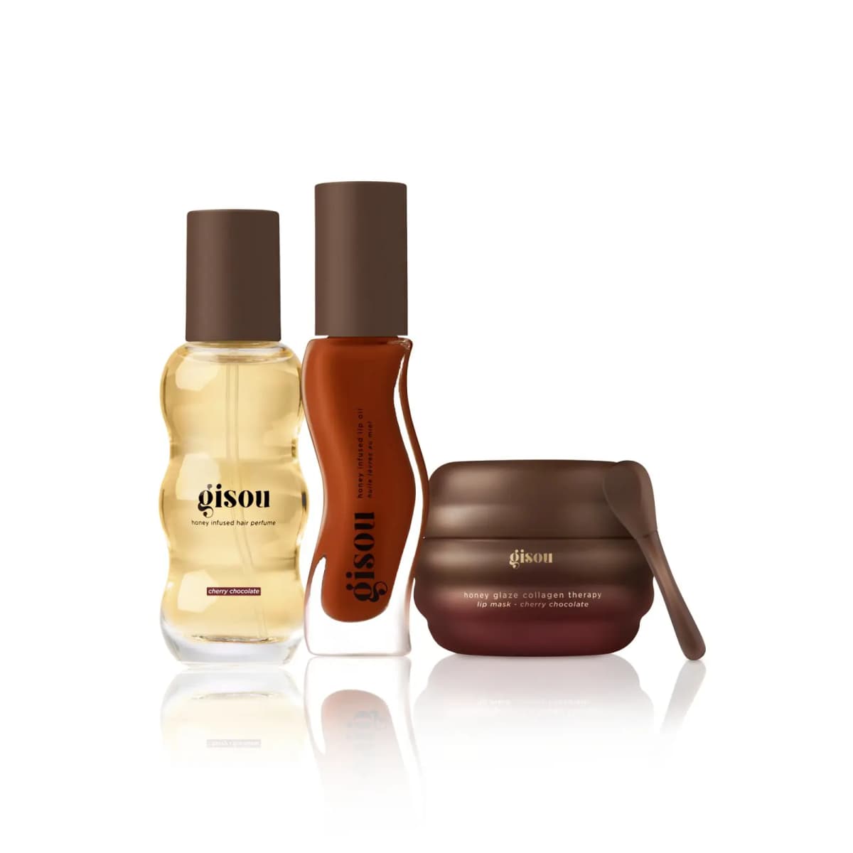 Hair perfume, rust-red lip oil and brown ribbed lip mask jar with spatula lined up on white