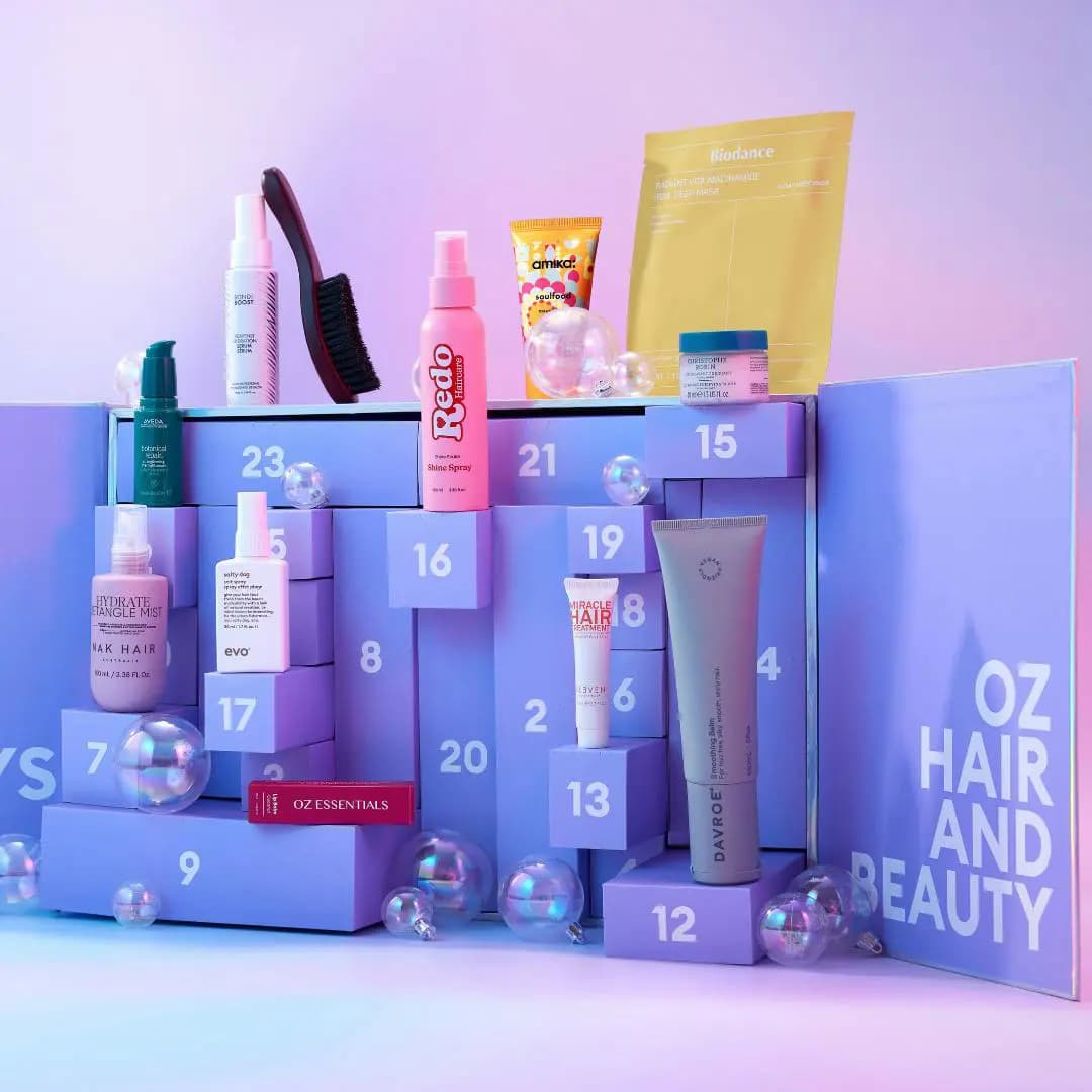 Products posed on open purple drawers with iridescent baubles, including Redo spray, Davroe balm and Aveda serum