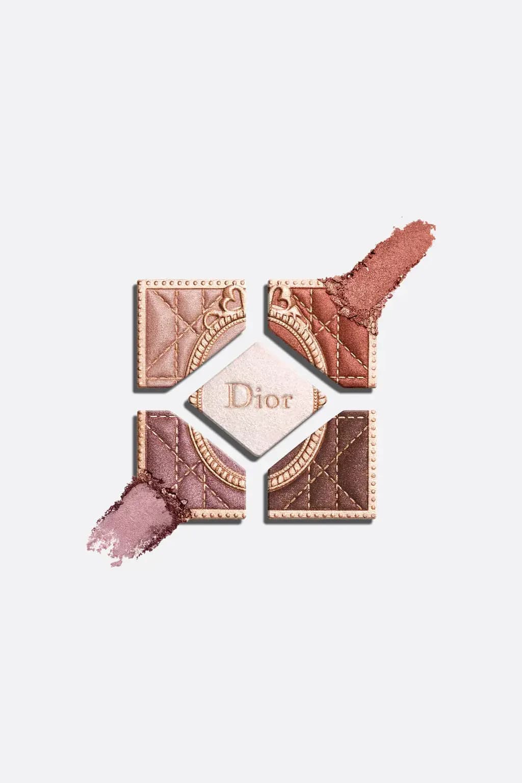 Five Dior eyeshadow pans laid apart with copper and mauve shimmer swatches smudged at the corners