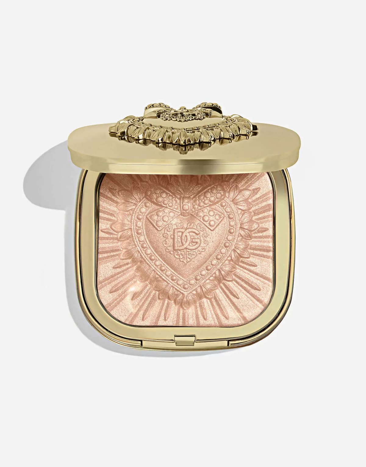 Open gold compact holding a peachy-pink shimmer highlighter with a sunburst heart and bow design