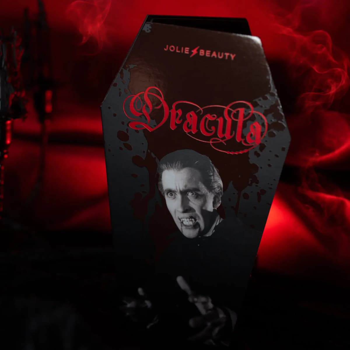 Upright coffin-shaped Dracula box with red foil logo and black-and-white fanged vampire image amid red smoke