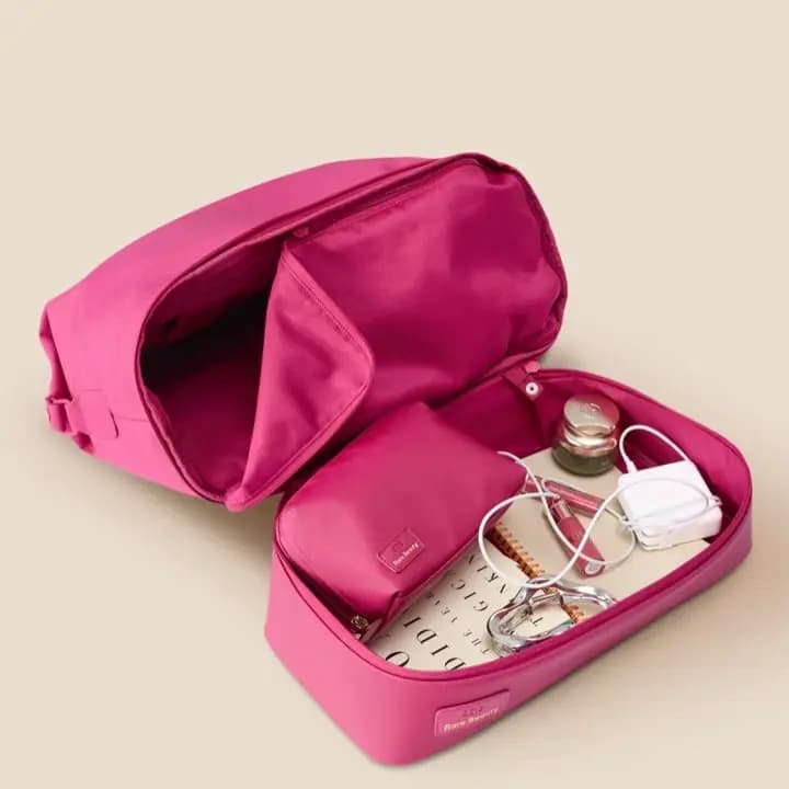 Open tote's bottom compartment holding a pouch, notebook, charger, jar and lip gloss
