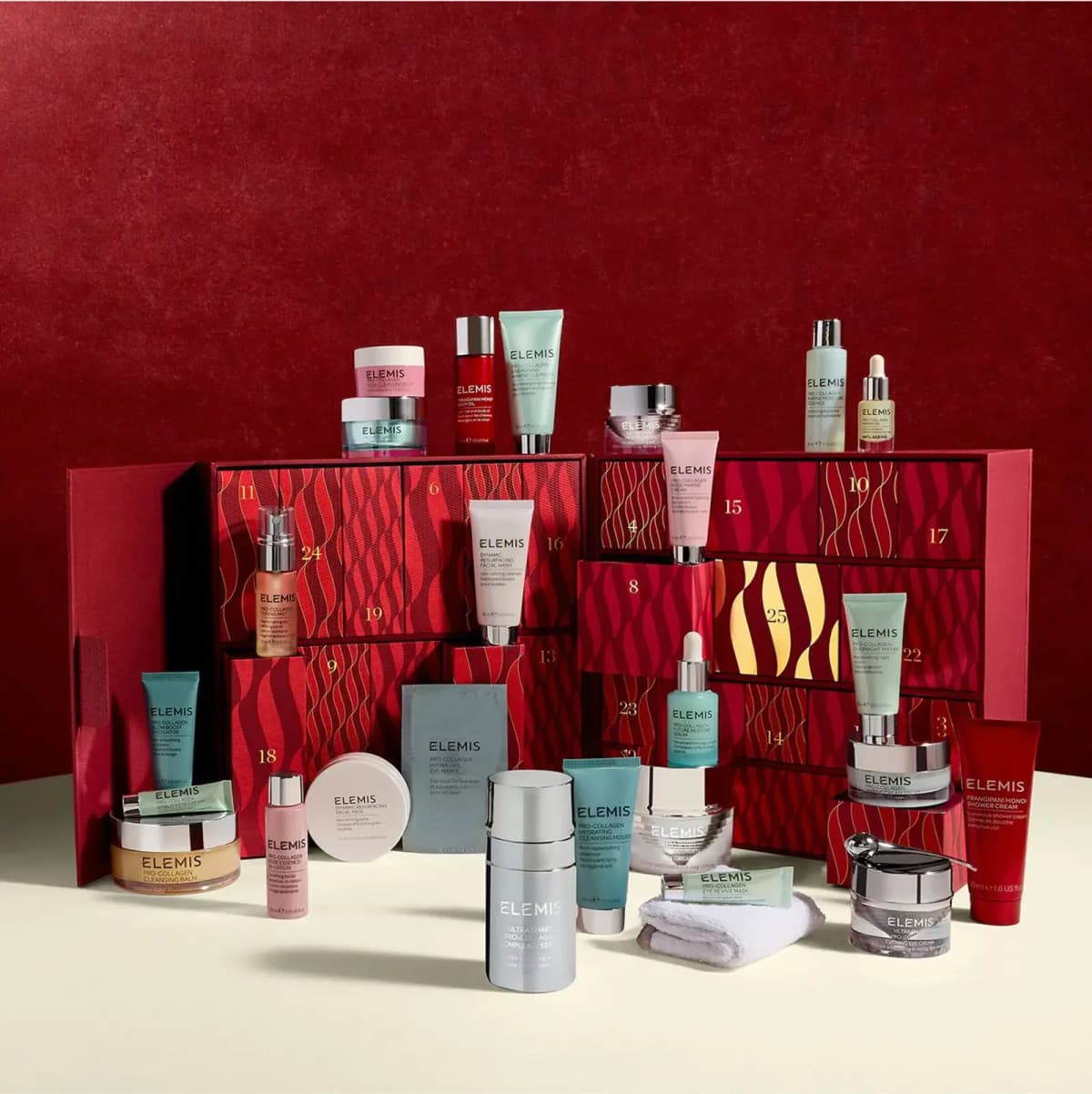 Open ELEMIS advent calendar with numbered red drawers, surrounded by Pro-Collagen skincare products on a red backdrop