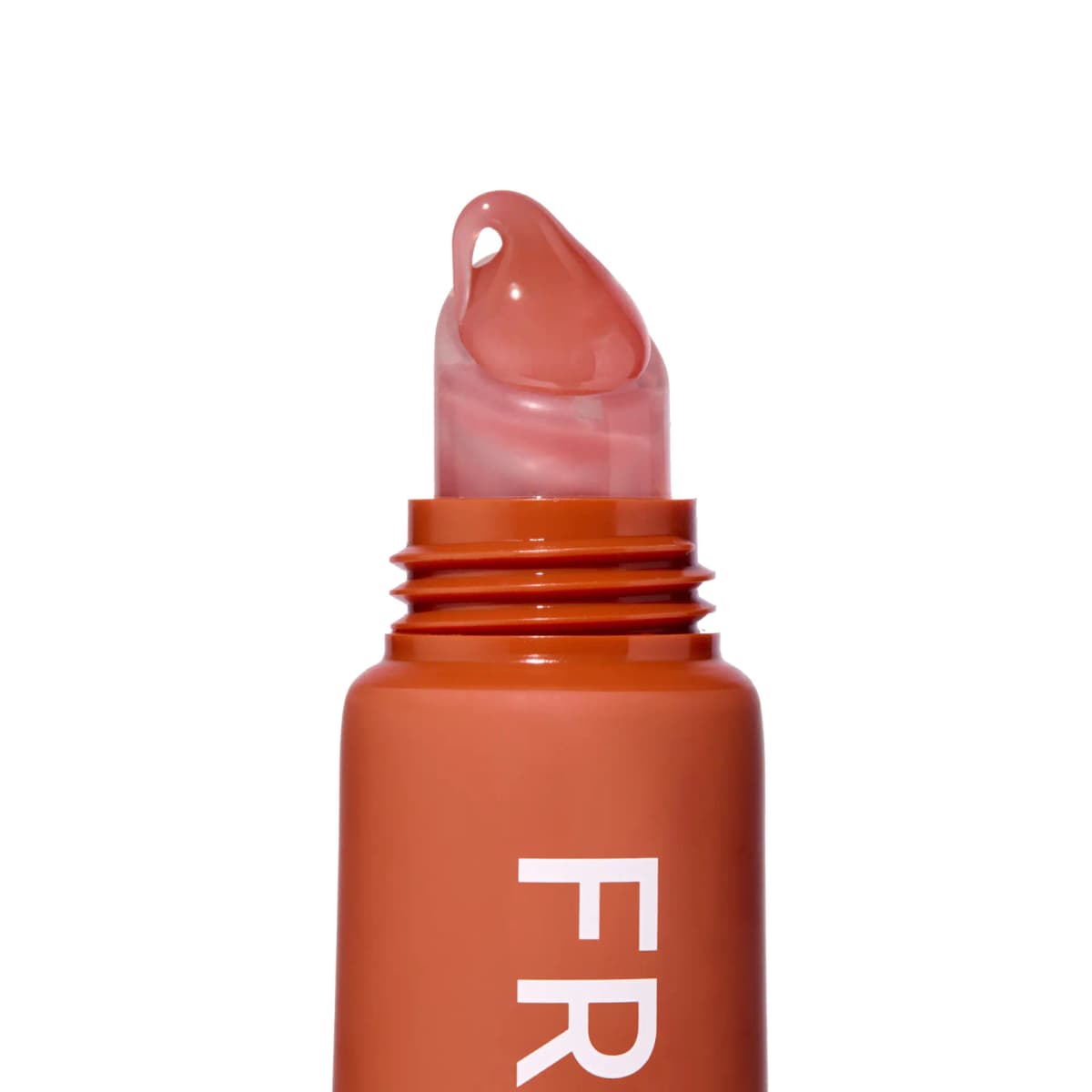 Close-up of the uncapped tube's angled clear tip topped with a glossy dollop of sheer peachy-pink balm