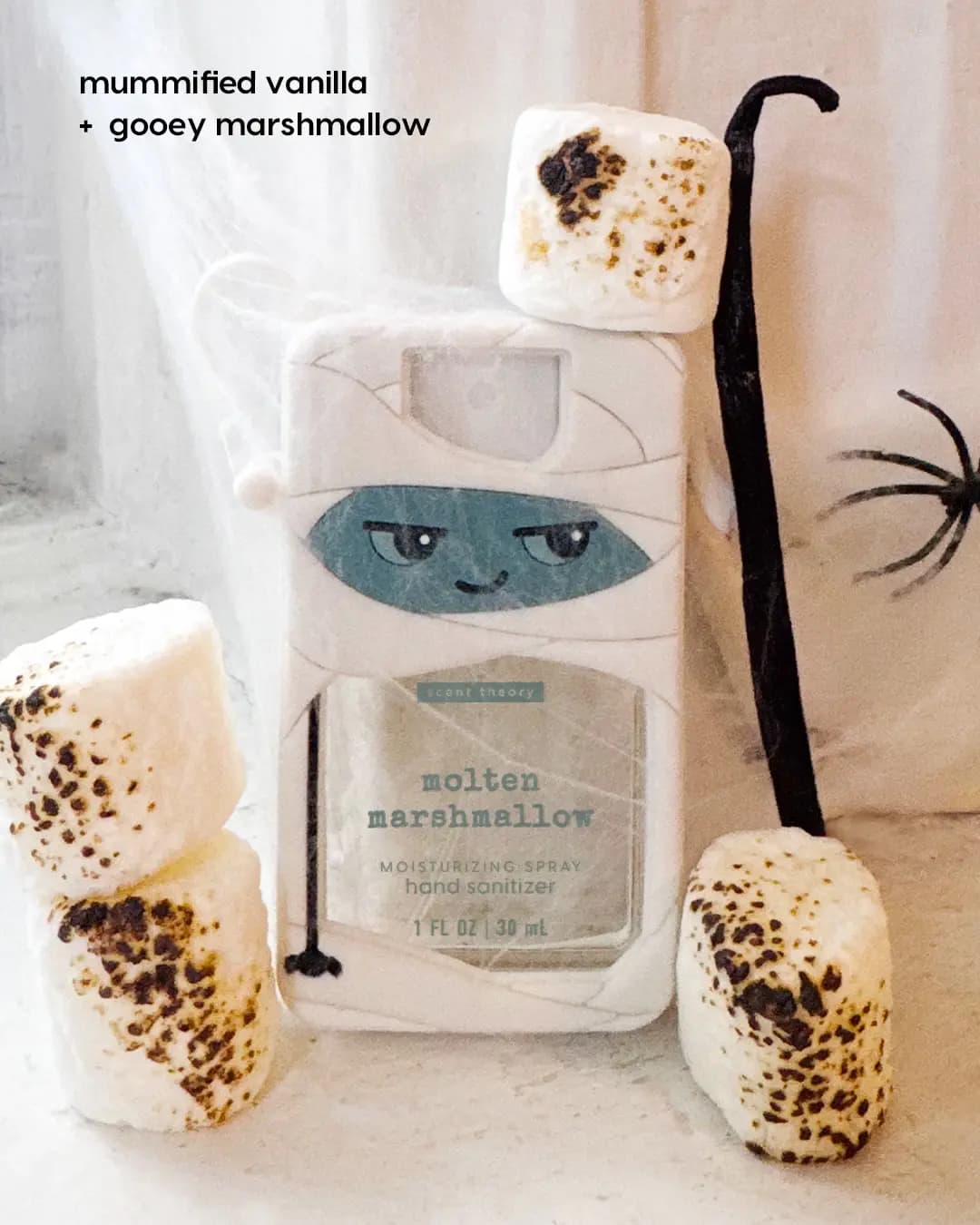 Molten Marshmallow sanitizer in a white mummy holder surrounded by toasted marshmallows and a vanilla bean