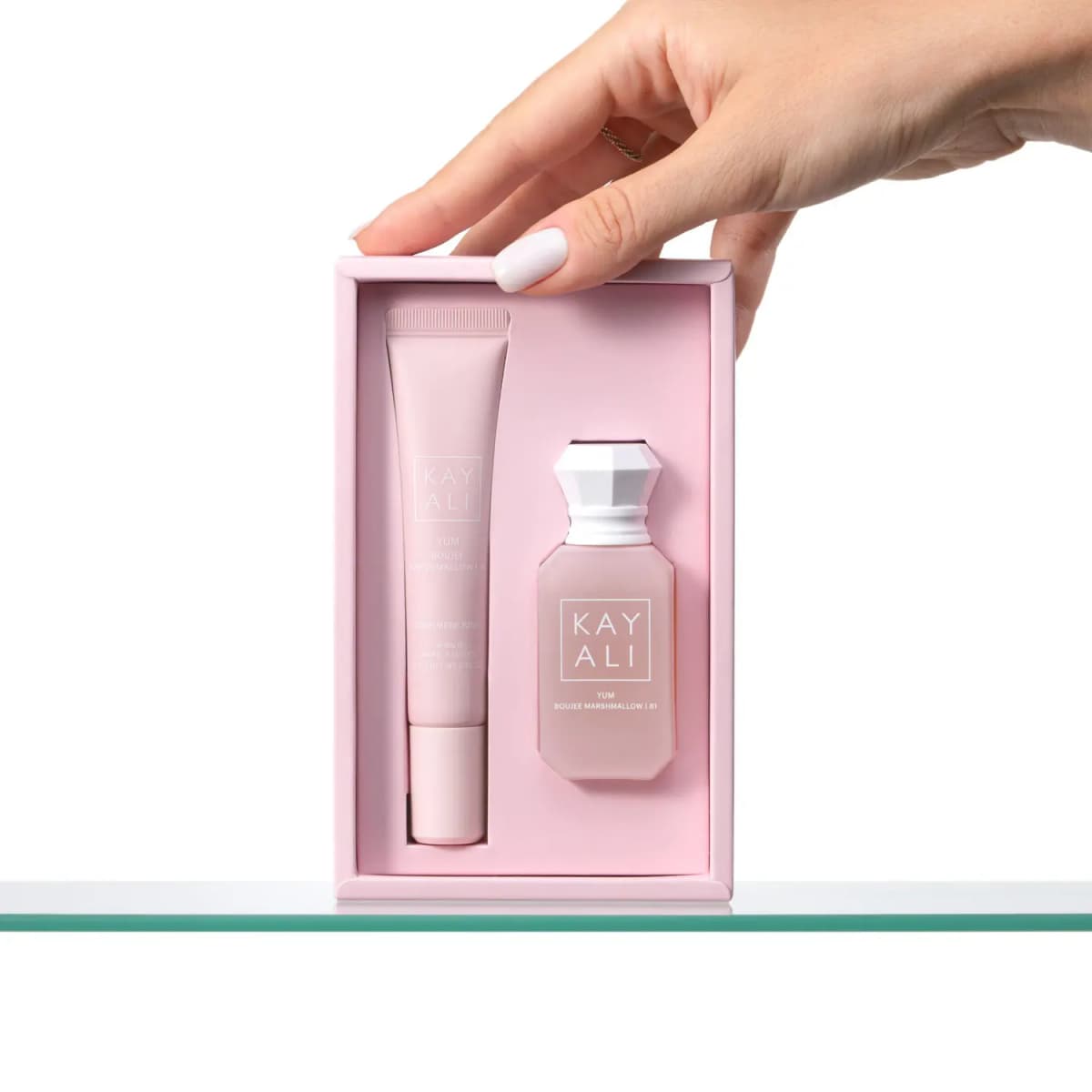 Hand opening the pink box to show the lip balm and Boujee Marshmallow perfume nestled inside