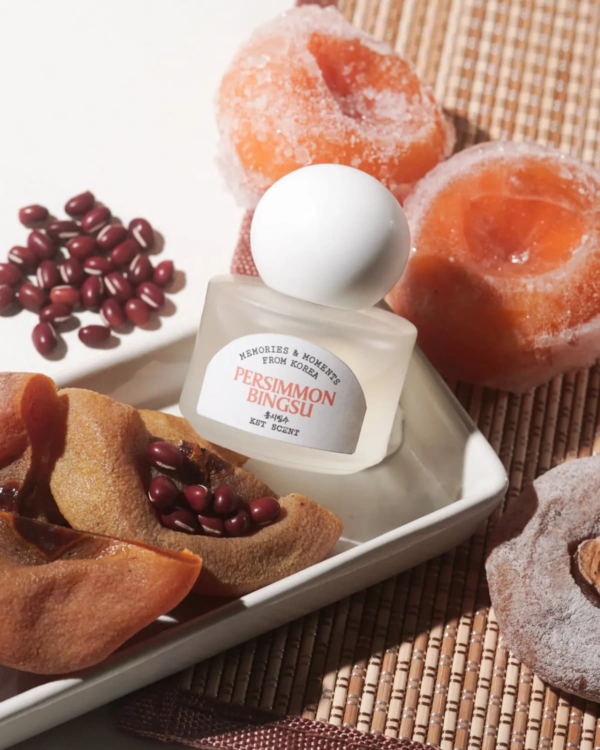 The bottle on a white tray with dried persimmons, adzuki beans and frosted persimmons on a bamboo mat