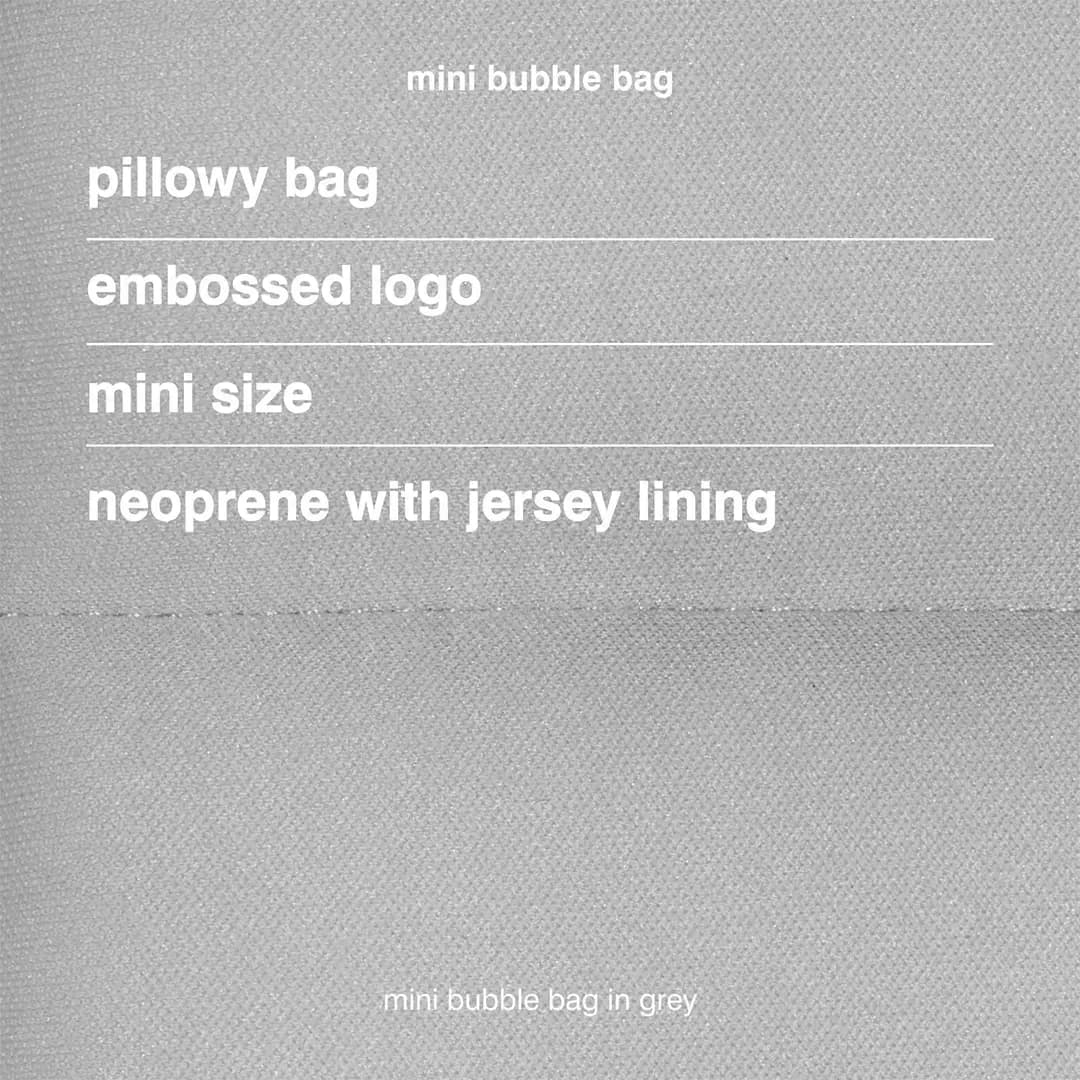 Close-up of grey textured fabric listing pillowy bag, embossed logo, mini size, neoprene with jersey lining
