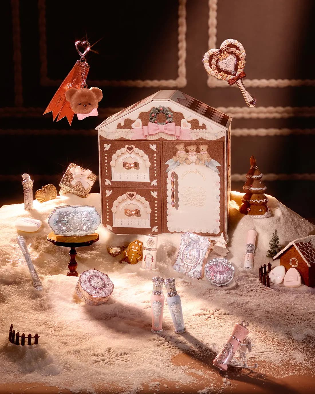Gingerbread-house box on sugary snow, surrounded by pastel makeup, a floating heart mirror and plush bear charm