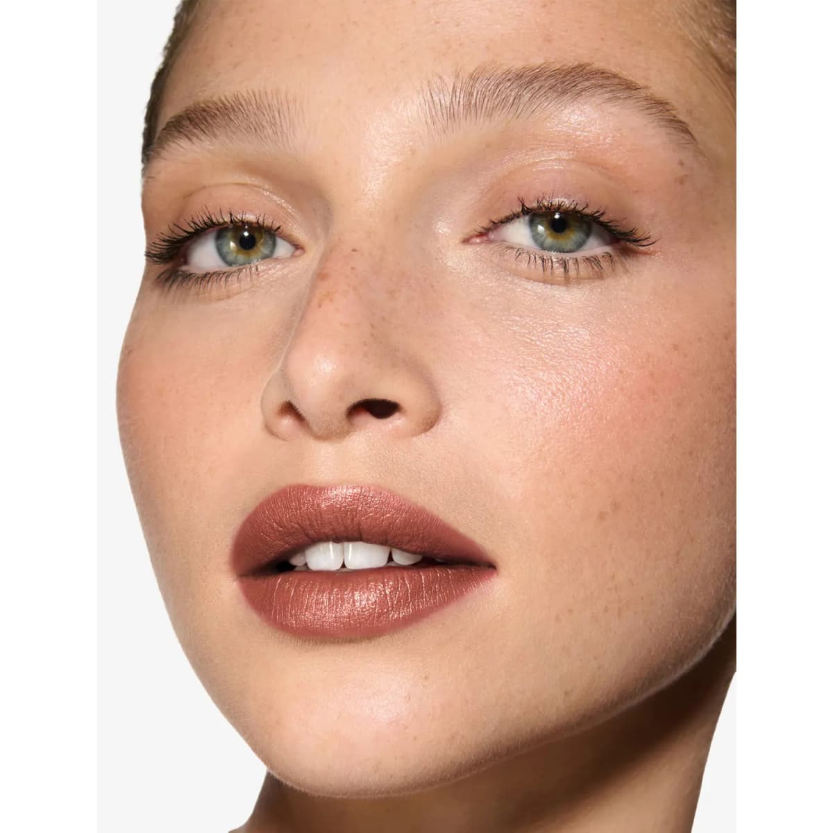 Fair, freckled model wearing a pearlised rosy-brown nude lipstick with soft, minimal eye makeup