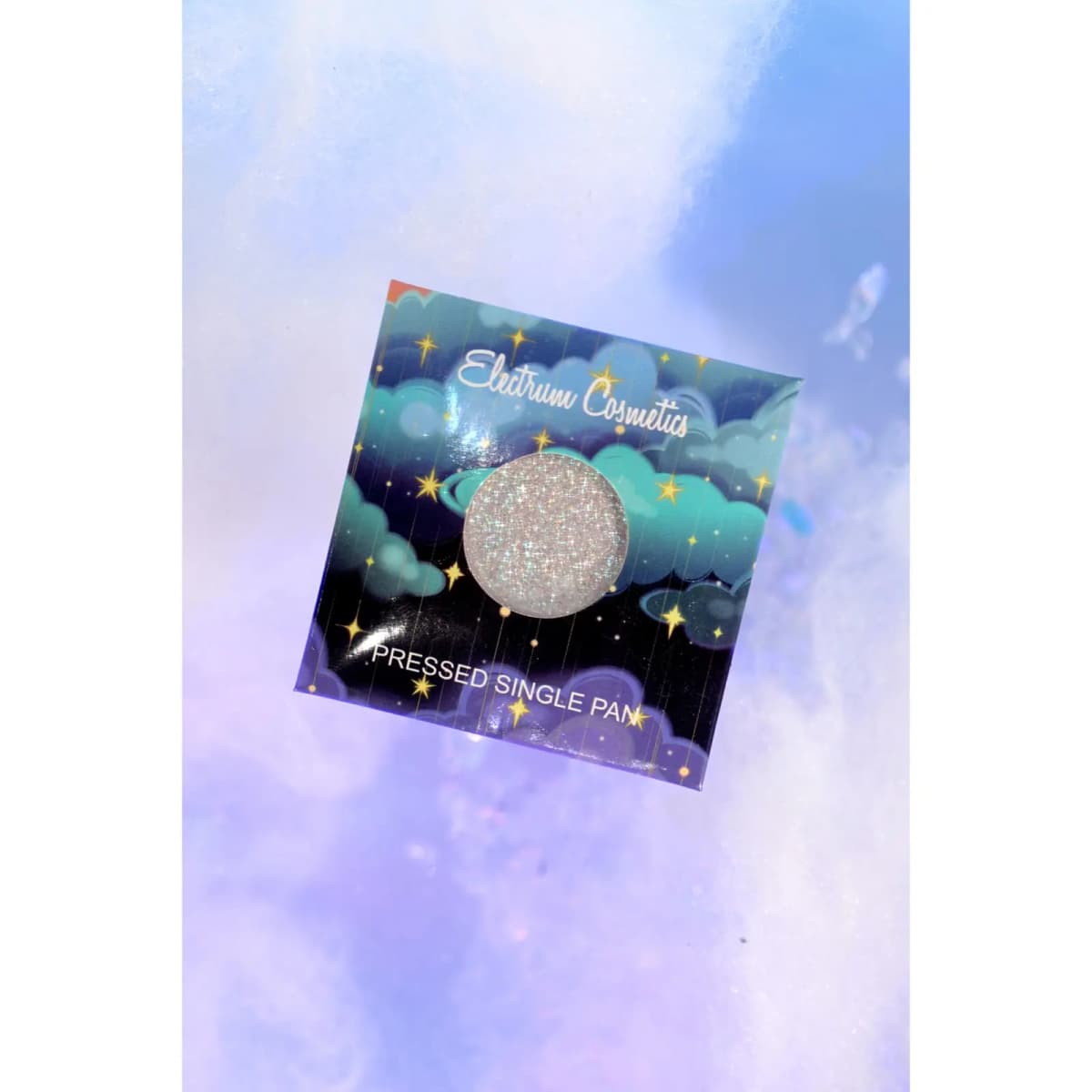 Electrum Cosmetics pressed single pan card with teal clouds and gold stars around a holographic silver shade