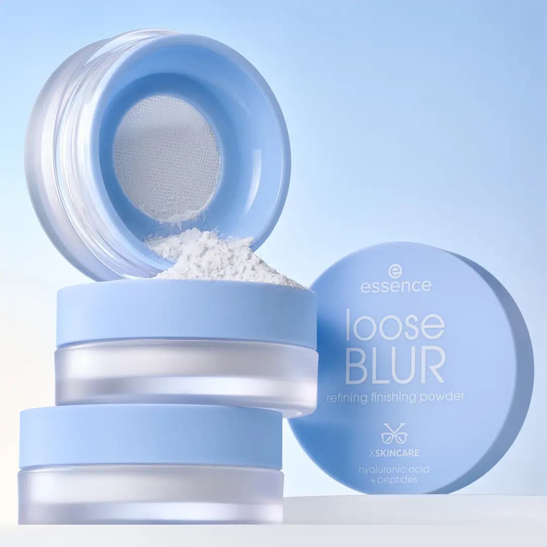 Stacked loose BLUR jars, one open with white powder spilling from the sifter, lid propped beside on light blue