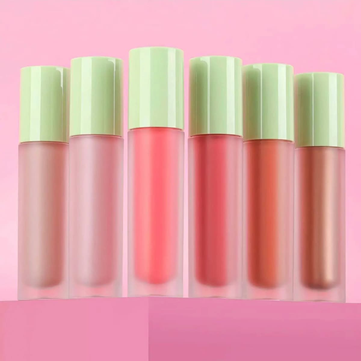 Six frosted tubes of Pixi LiquidGlow Blush with pastel green caps arranged in a fan on a pink background.