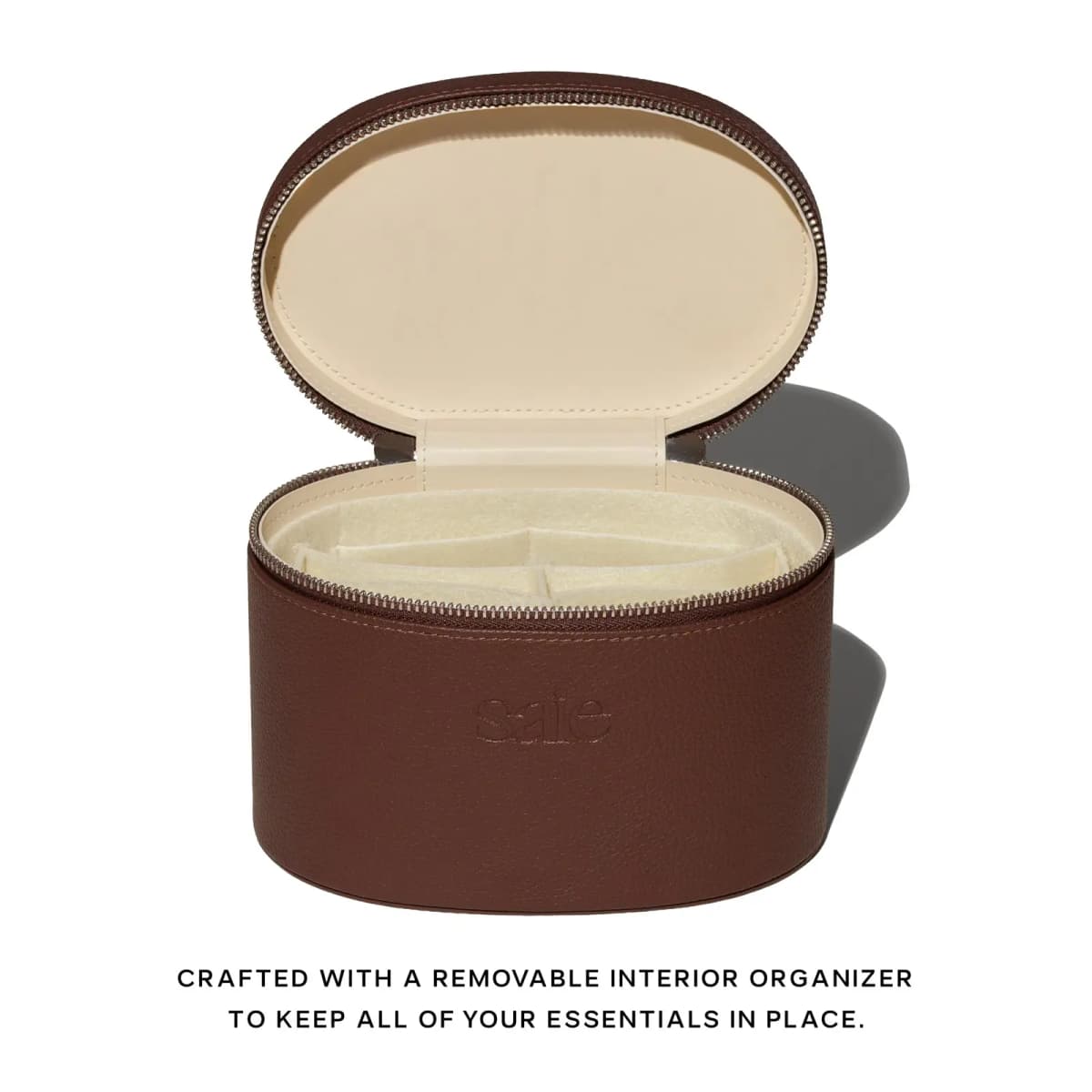 Open brown Saie vanity case with cream lining and a removable felt organizer with compartments