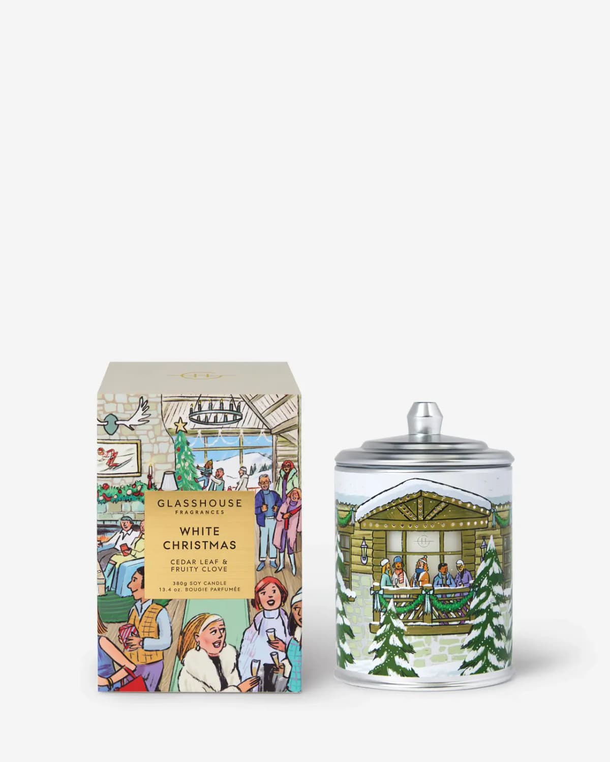 White Christmas candle with silver lid and snowy chalet tin beside its cream-topped ski-lodge box on white
