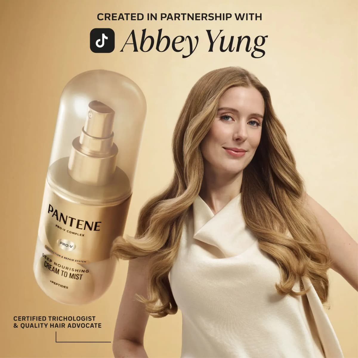 Abbey Yung, certified trichologist, holding the Pantene Deep Nourishing Cream to Mist Spray in a gold campaign image
