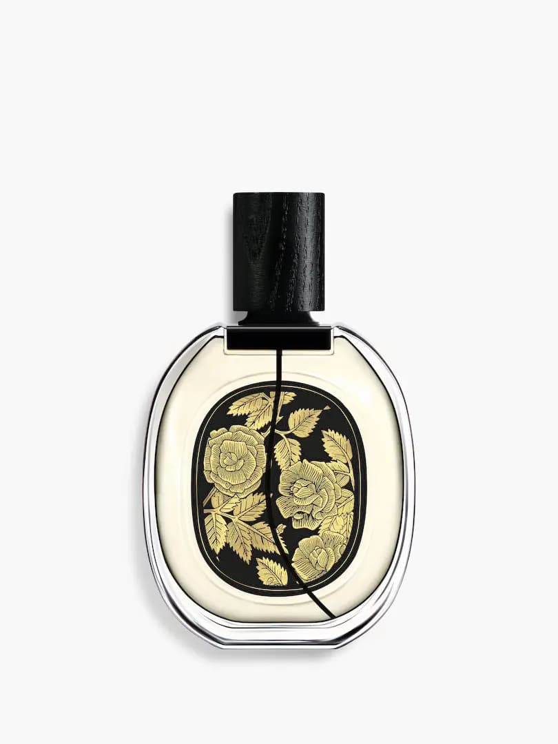 Back of Eau Rose bottle with a black label covered in engraved gold roses and leaves