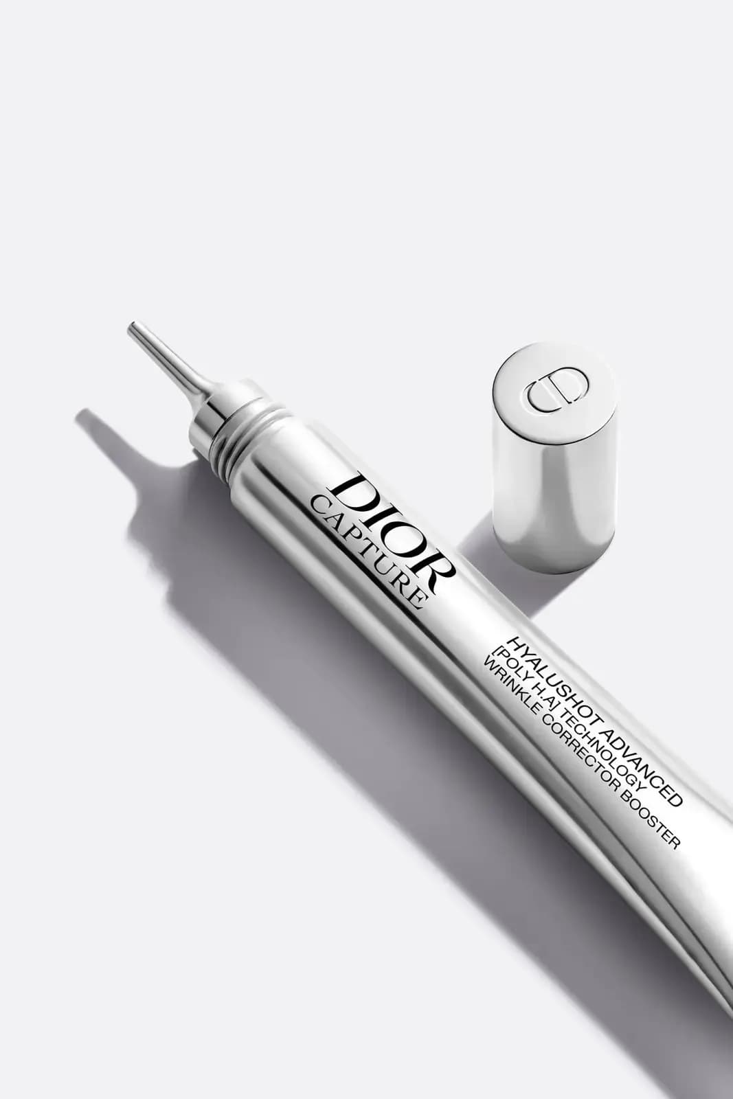 Silver tube uncapped to reveal a fine metal needle-tip applicator, with the Dior-logo cap lying beside it