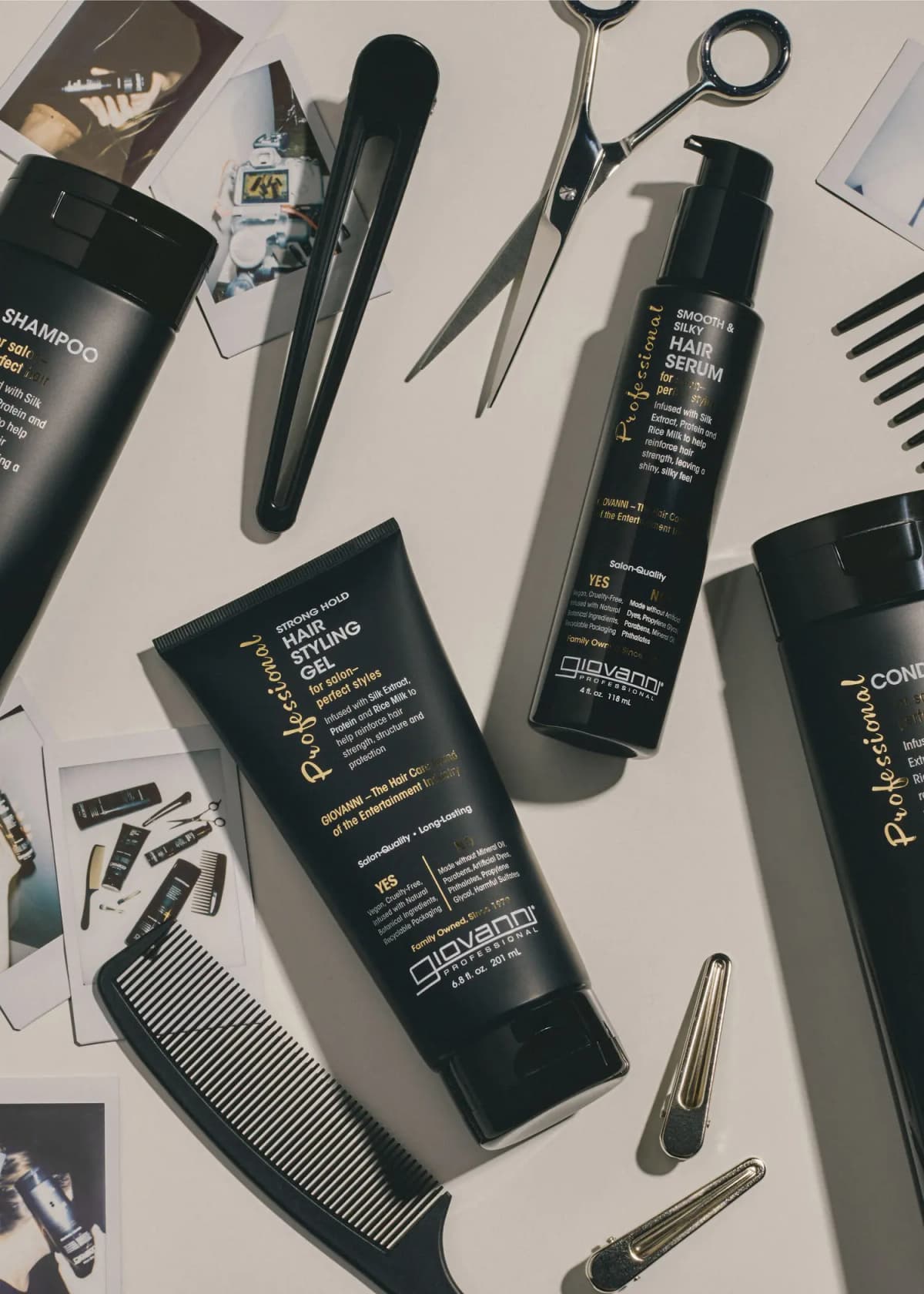 Flat lay of Giovanni Professional gel and serum among scissors, combs, clips and instant photos on a pale surface.