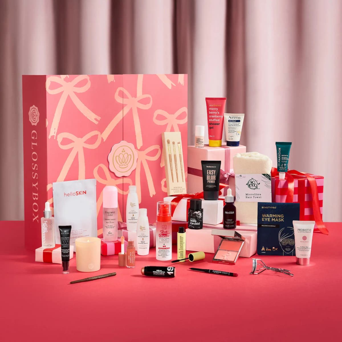 Closed bow-print Advent Calendar surrounded by its products, incl. Huda Beauty primer, Medik8 serum and helloSKIN mask