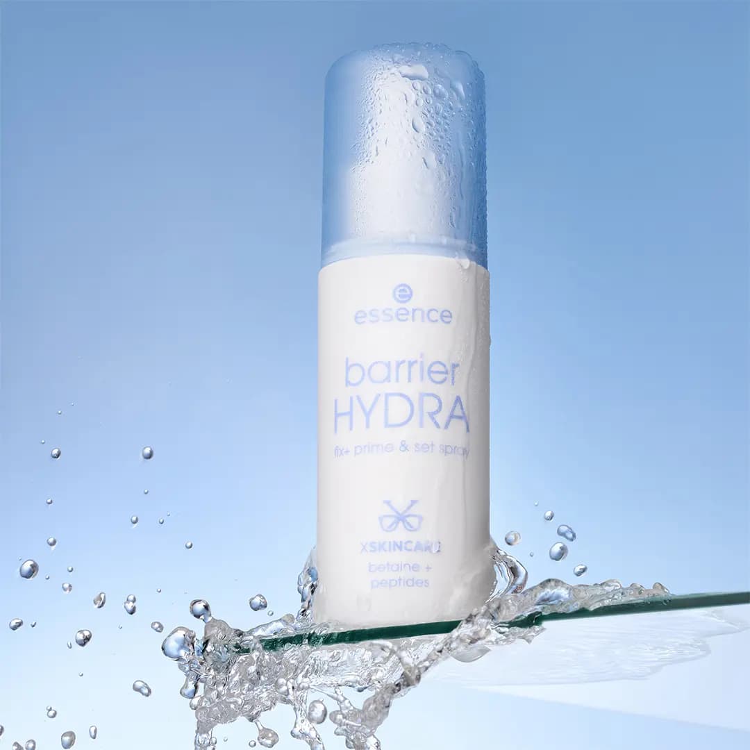 Barrier HYDRA spray bottle covered in water droplets, standing in a splash on a glass shelf against blue