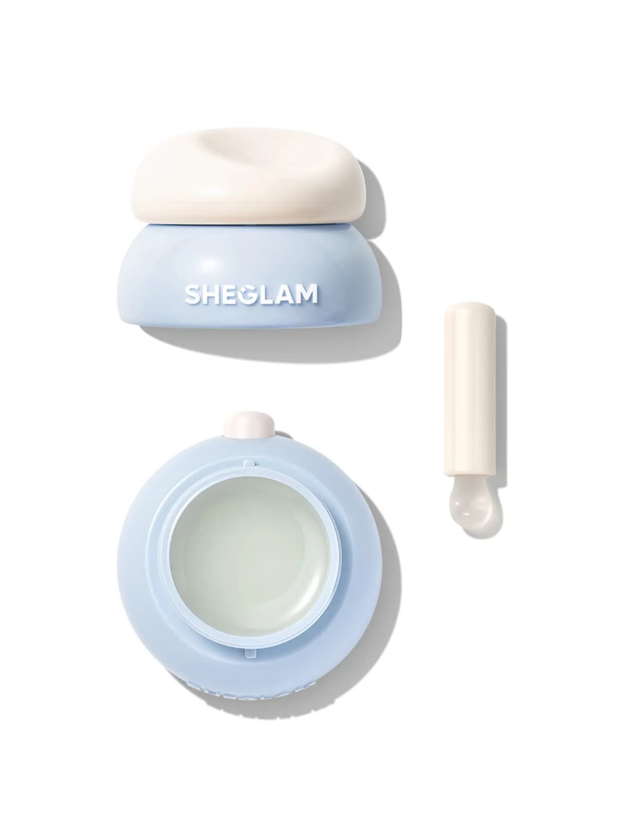 Blue jar with cream lid, open pan of pale translucent green-white lip mask and white applicator on white