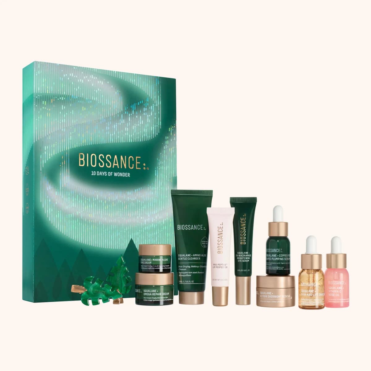 Biossance 10 Days of Wonder box with holographic Northern Lights foil beside its jars, tubes, dropper bottles and tree clips