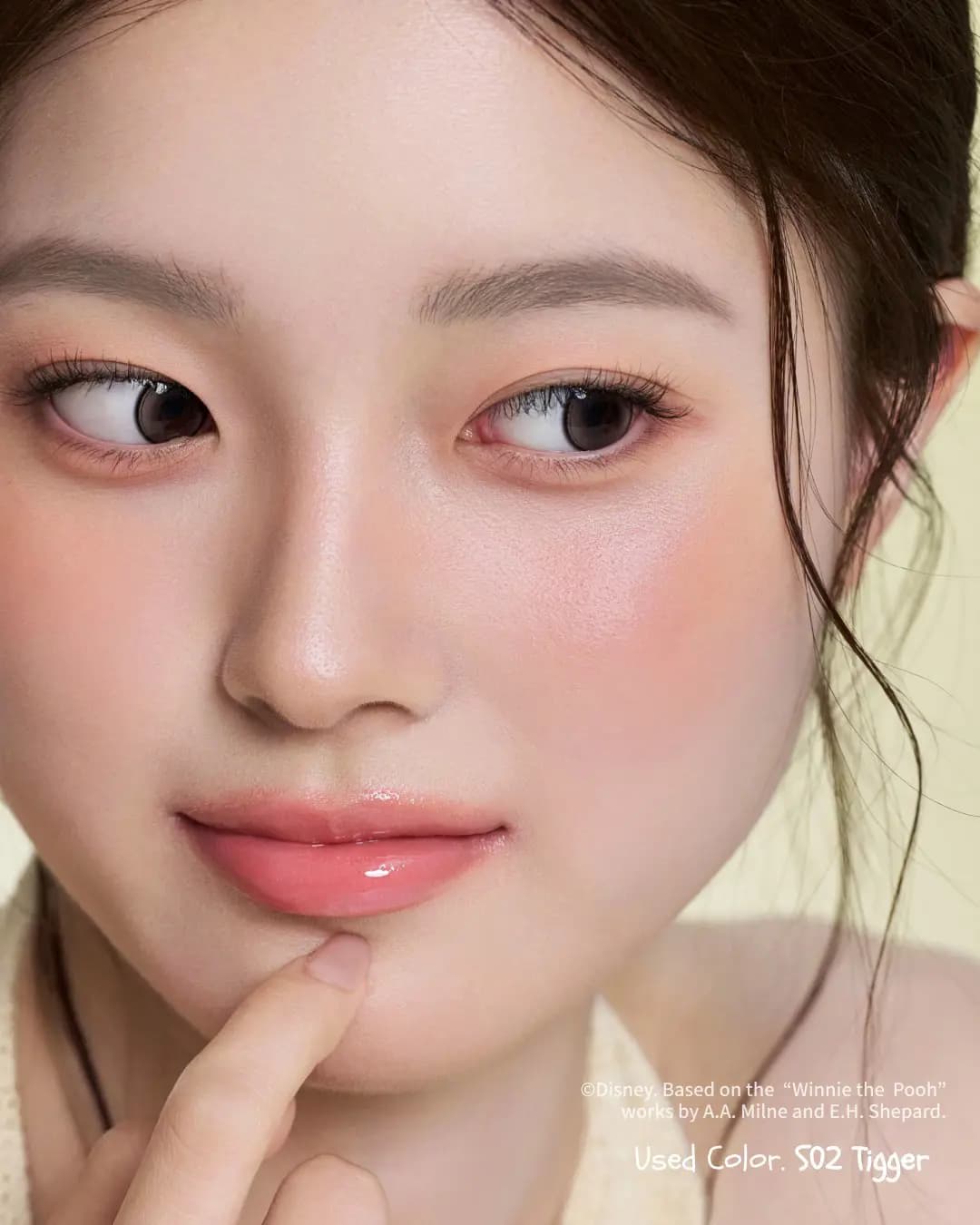 Close-up of model with coral flush and peachy eyes wearing S02 Tigger, finger touching glossy pink lips