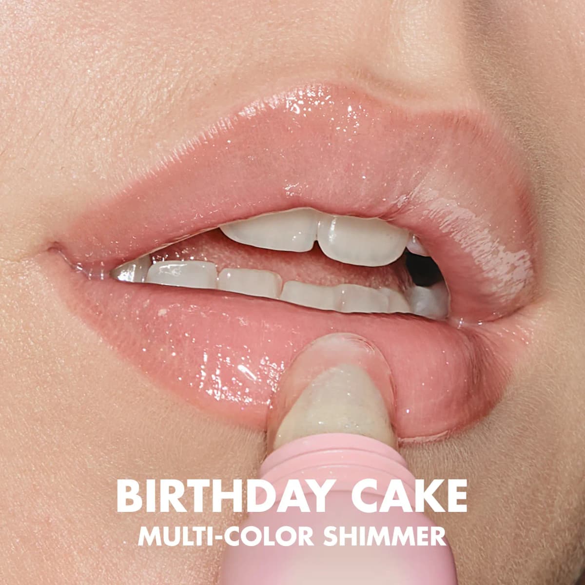 Close-up of the angled tip applying glossy, sparkly balm to lips, labelled Birthday Cake multi-color shimmer