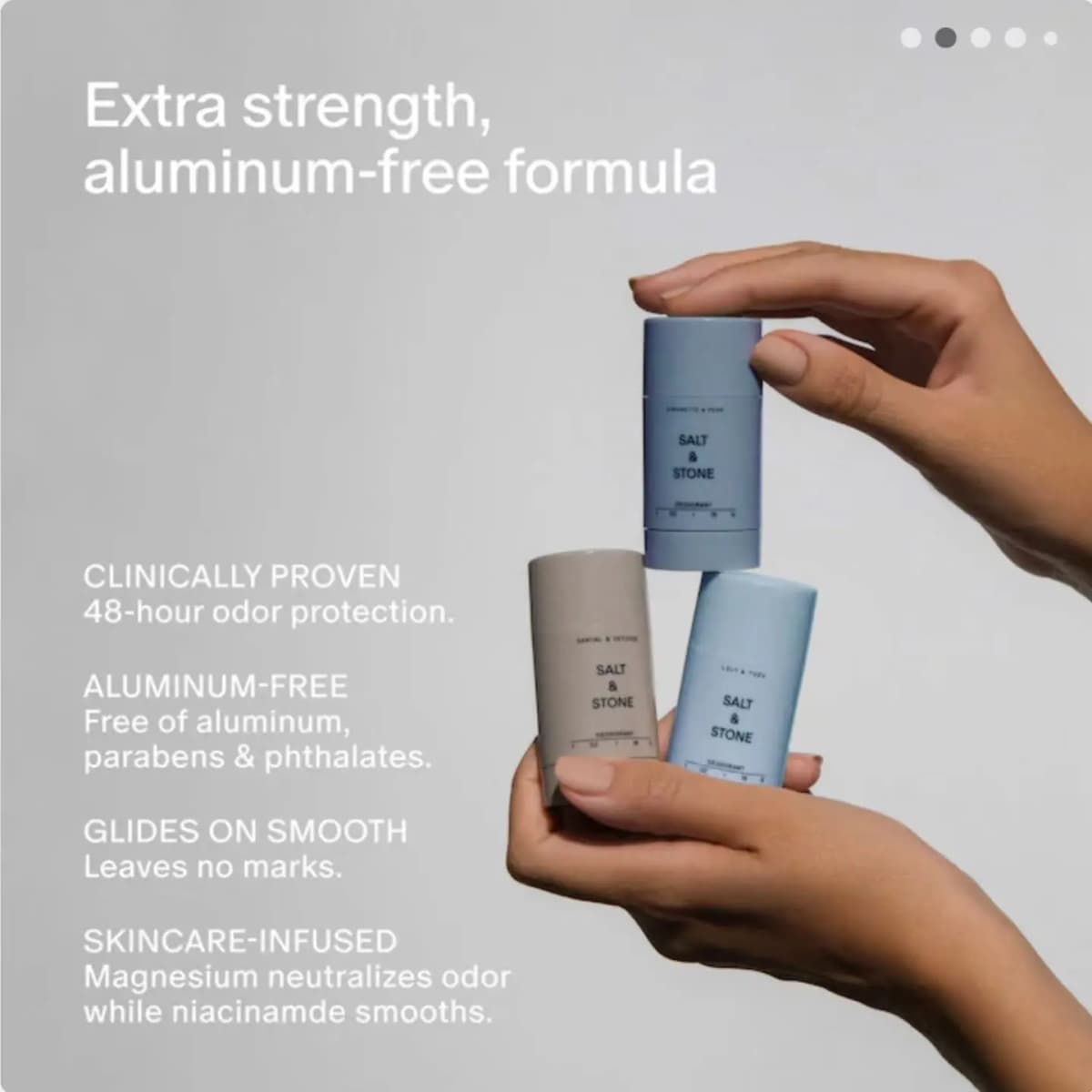 Hands holding three Salt & Stone deodorant sticks beside text listing clinical, aluminum-free, smooth glide
