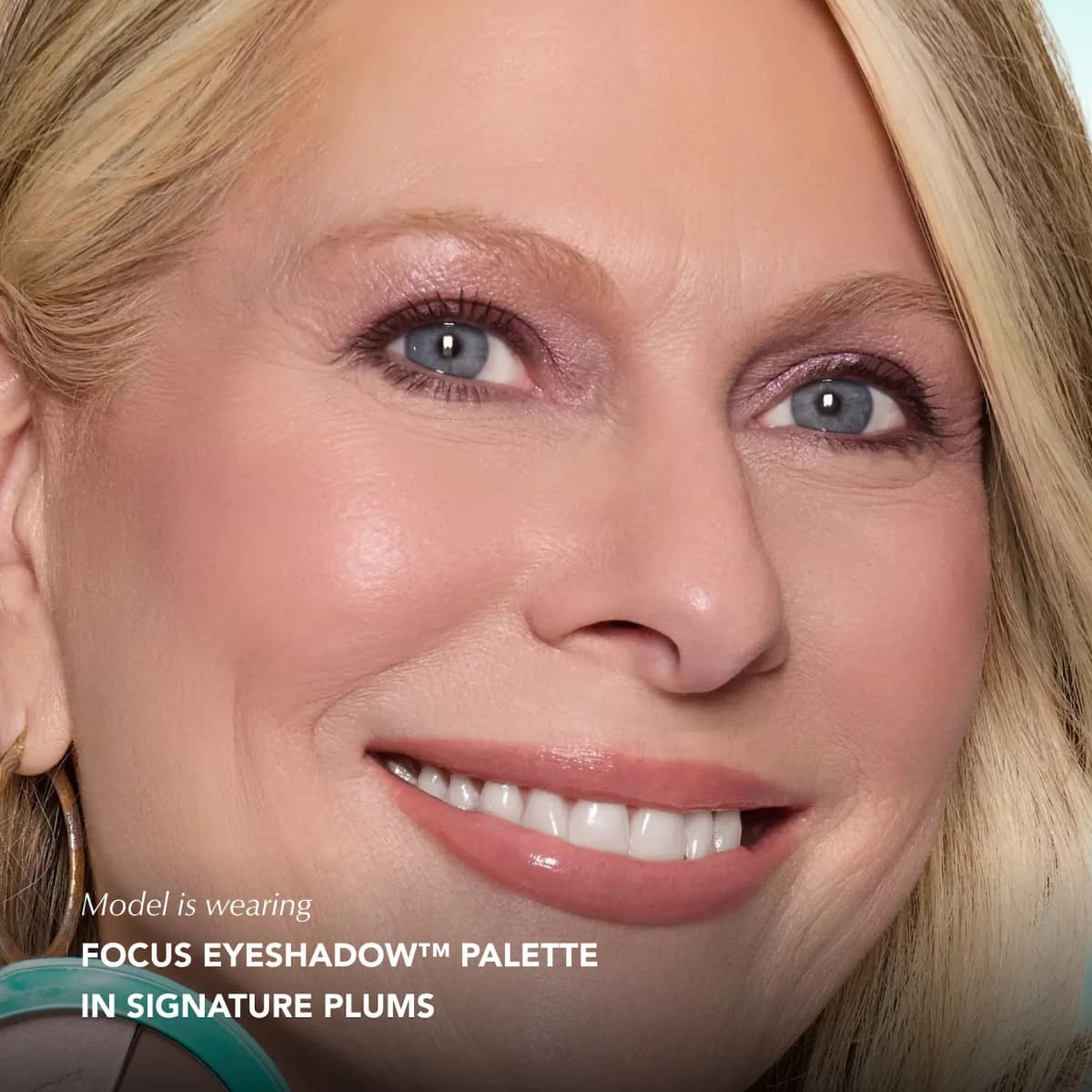 Smiling blonde model with blue eyes wearing shimmery mauve eyeshadow from Signature Plums.