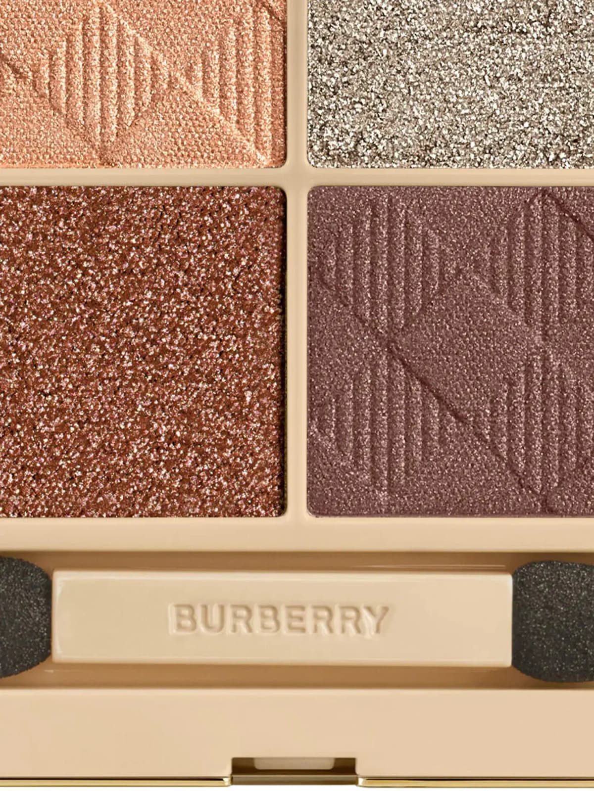 Close-up of Winter Gold pans: embossed peach, sparkly silver-taupe, glittery copper and plum satin above an applicator
