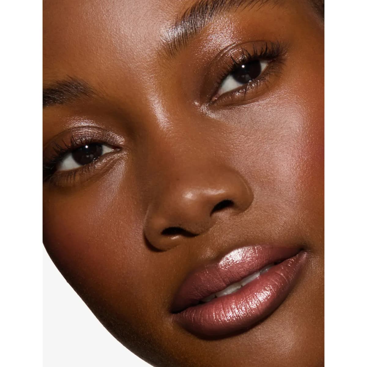 Close-up of a deep-skinned model wearing a shimmering rosy-brown nude lip with glowing skin
