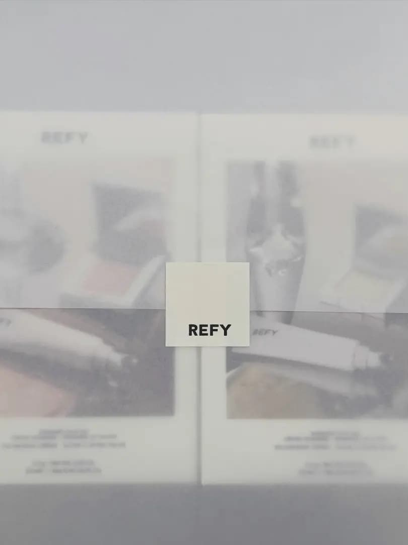 Two blurred REFY product boxes behind a small cream card printed with the black REFY logo.
