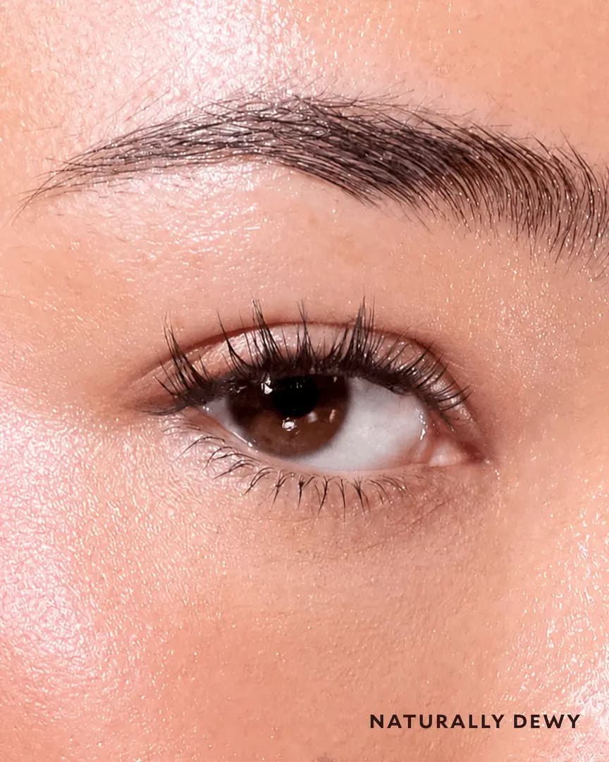 Close-up of a brown eye on fair, glowing skin with light, wispy Naturally Dewy lash clusters