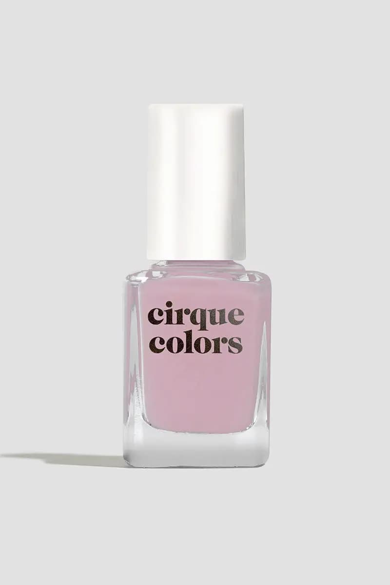 Single bottle of pale lilac pink polish with a white cap on a light grey background