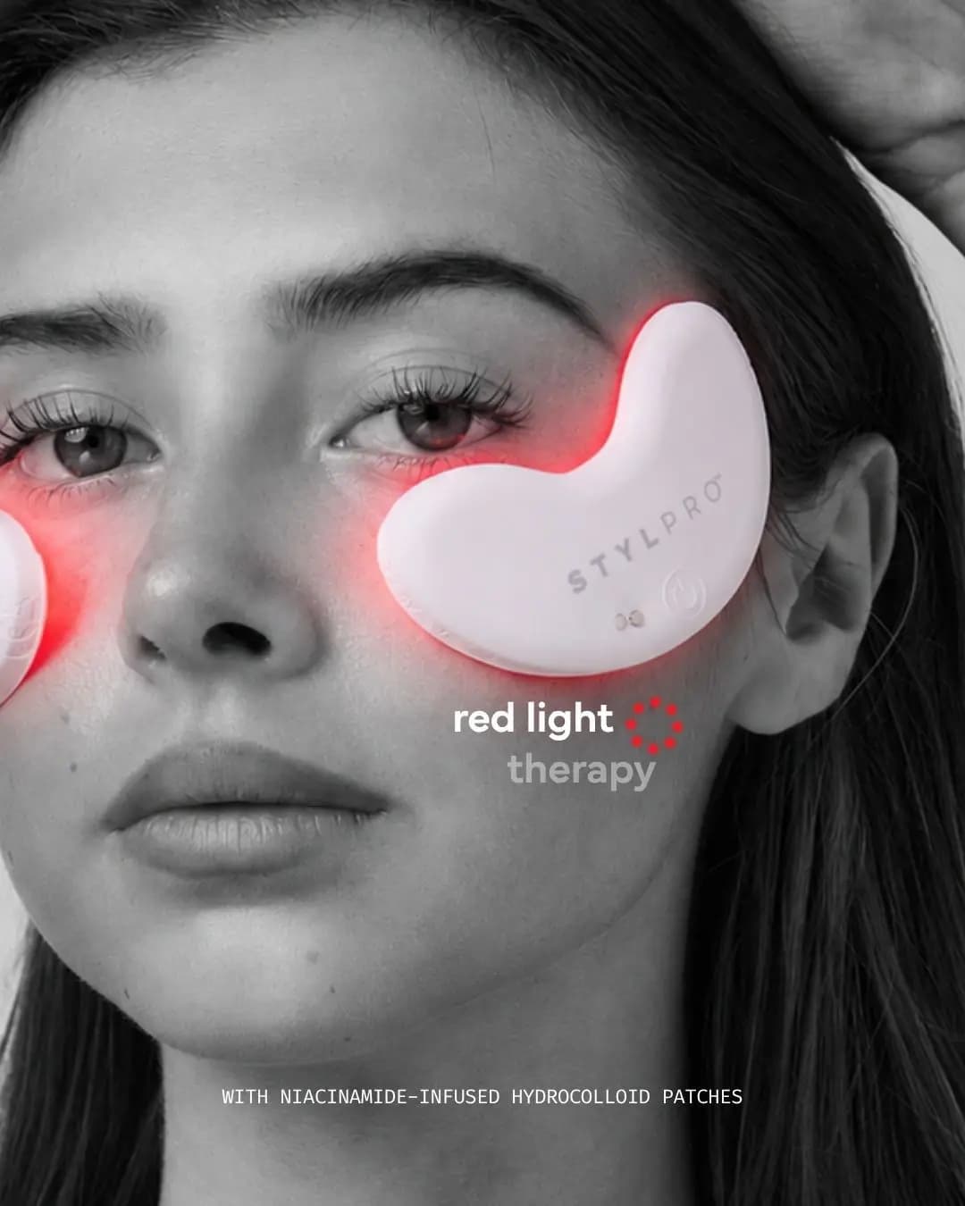 Black-and-white portrait of a model wearing white STYLPRO LED patches under her eyes, glowing red