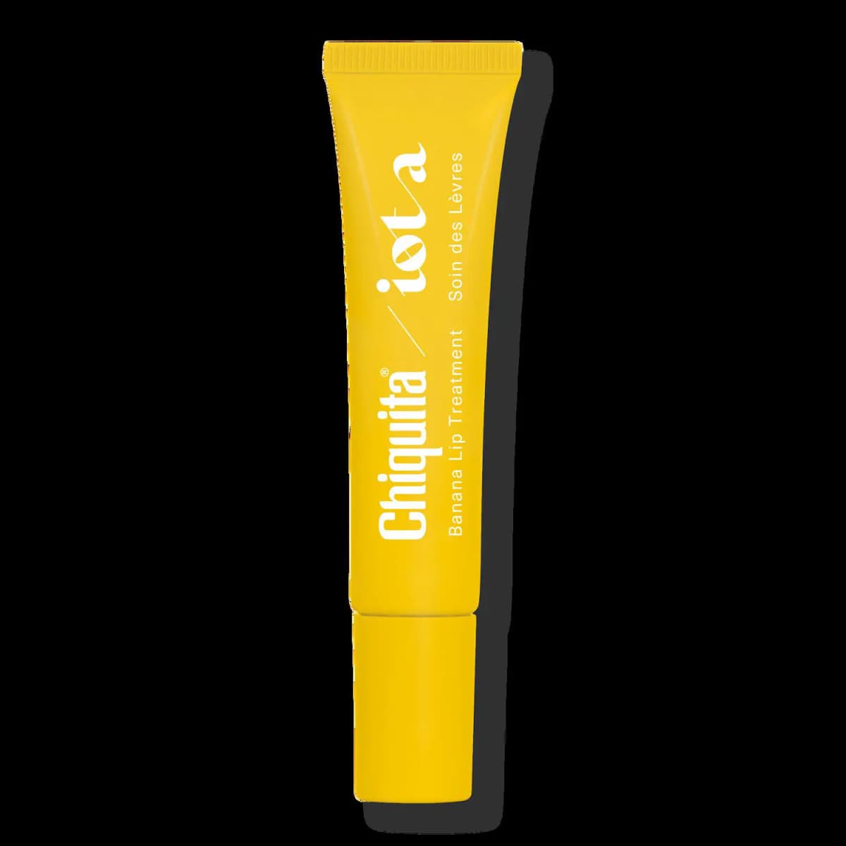 Yellow squeeze tube with white Chiquita / iota branding, Banana Lip Treatment and Soin des Lèvres text, on black