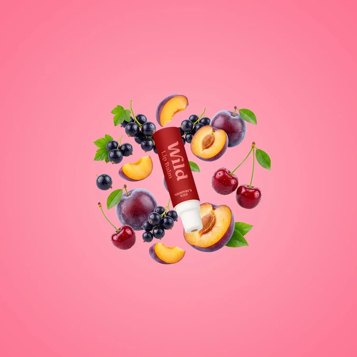 Red Wild Vampire's Kiss lip balm floating among plums, cherries and blackcurrants on a soft pink background