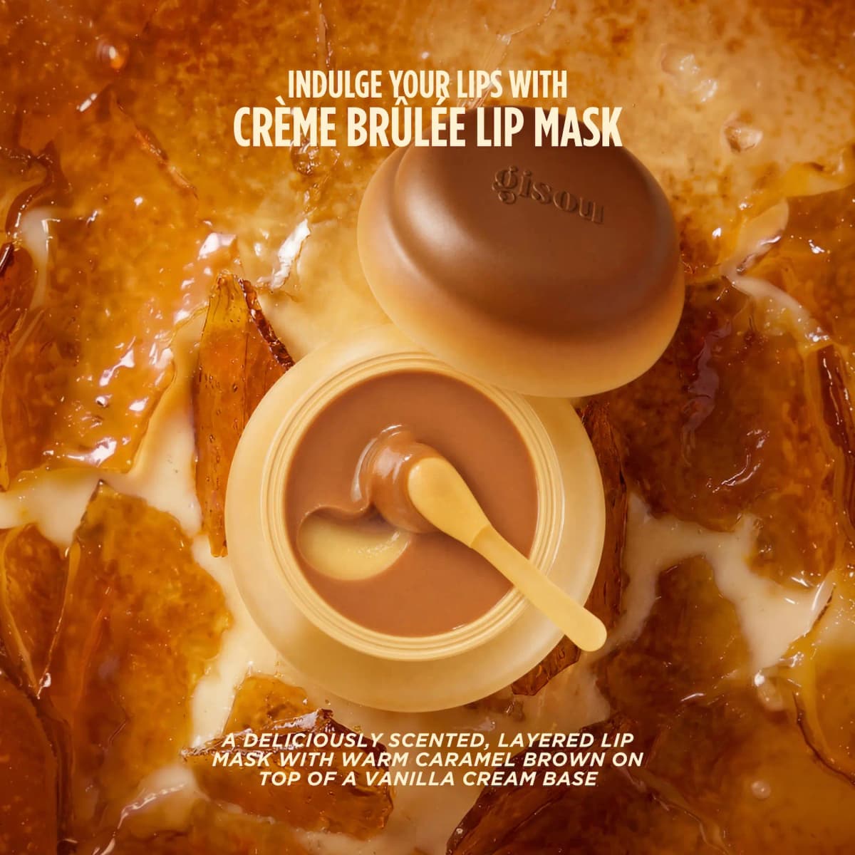 Open lip mask jar with brown caramel layer over vanilla cream, spatula and lid on crème brûlée shards