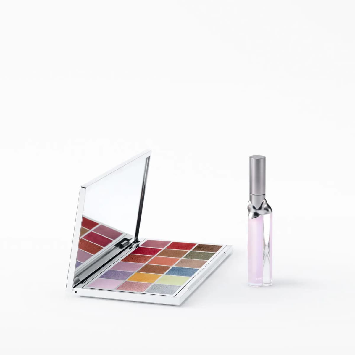 Palette angled open on a white surface next to the Aurora lip tube with sculpted metal neck